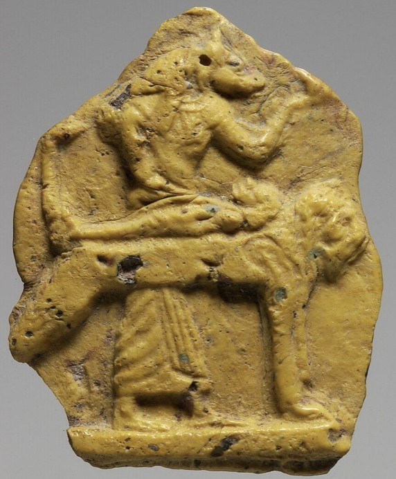 Yellow glass fragmentary inlay of Anubis attending a mummy on its bier Yellow glass fragmentary inlay of Anubis attending a mummy on its bier